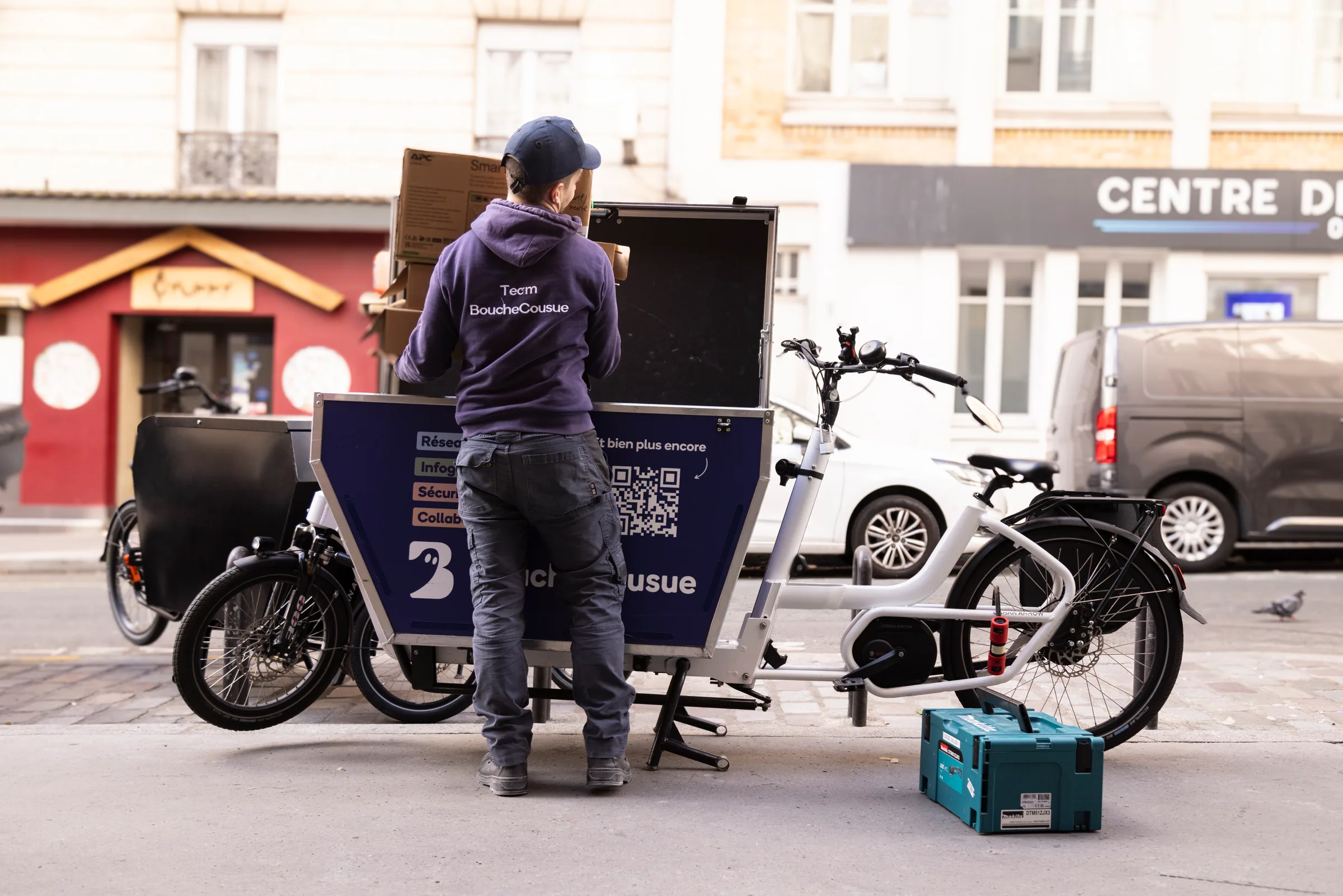 Technicien BoucheCousue chargeant du matériel dans un vélo cargo à Paris